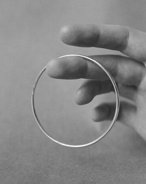 Plain rounded bangle held by a hand.