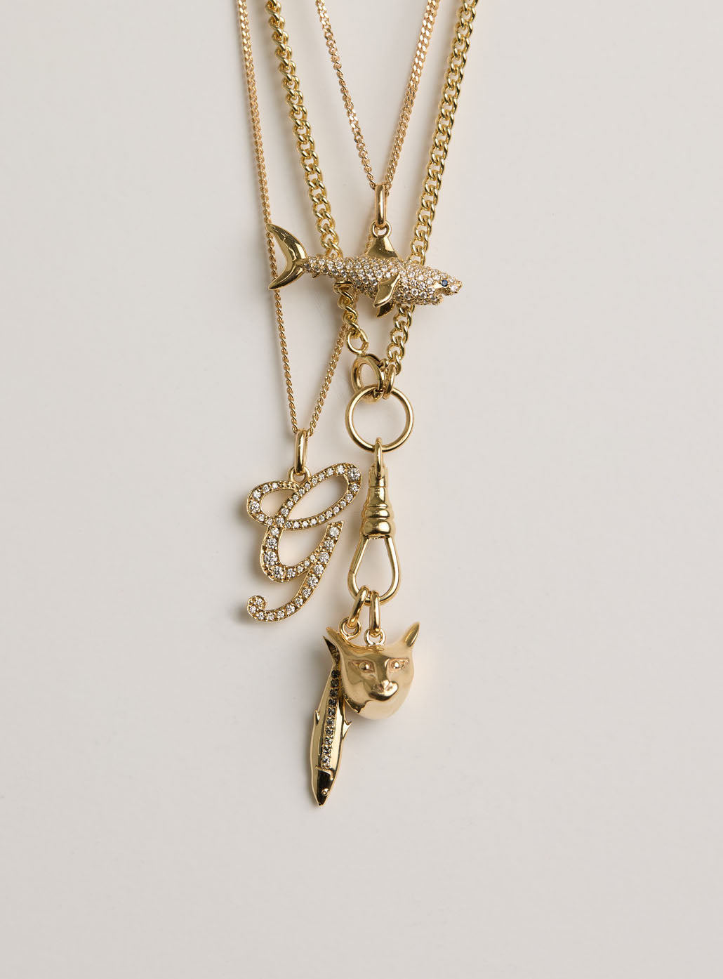 Gold necklace with various pendants on a light gray background