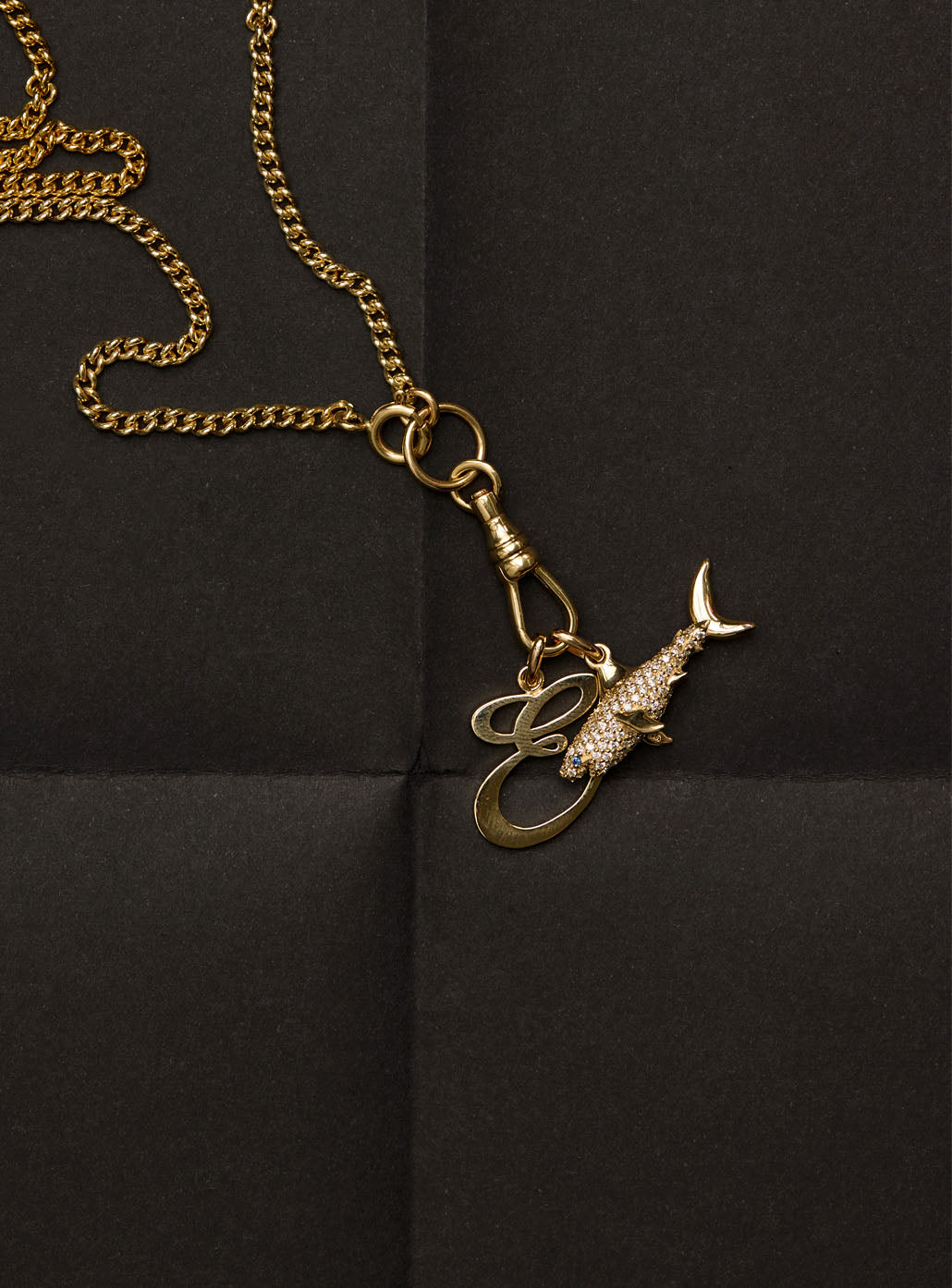 Gold necklace with a shark and letter pendants