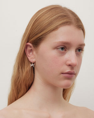 Silver bow hoop earrings worn on model