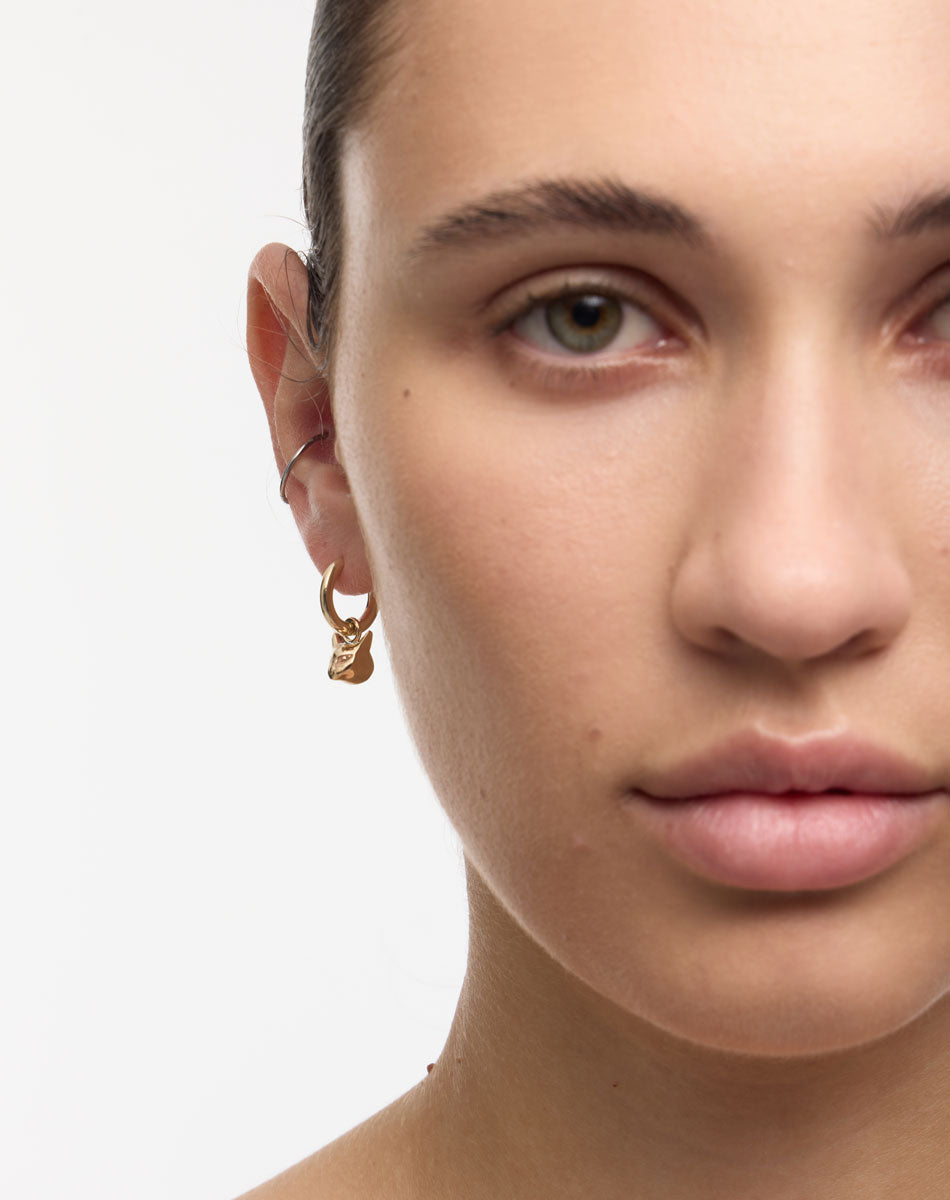 Close-up of a person wearing a gold cat earring 