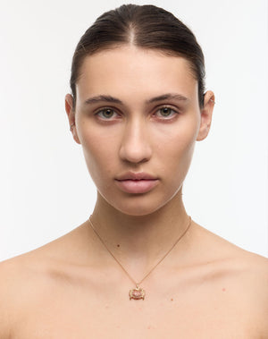 Woman wearing a gold crab charm necklace with a pave set red sapphires