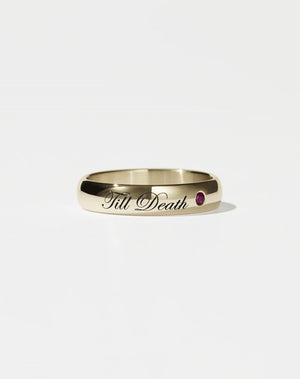 A half-round, yellow gold band ring with the phrase 'Till Death' engraved on it and a small ruby set on one side.