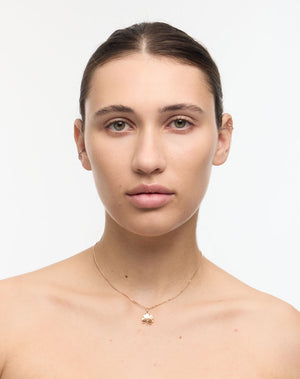 Woman wearing a gold necklace with a lucky four leaf clover pendant on a white background