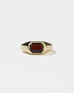 A gold ring with a red Garnet gemstone on a white background. Made by Meadowlark Jewellery in New Zealand.