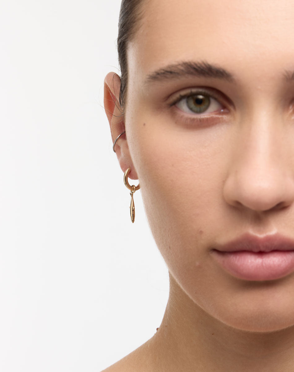 Gold hoop earrings with a sardine charm worn by a model