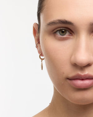Gold hoop earrings with a sardine charm worn by a model