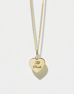 A gold fine chain necklace with a minimalist heart charm that reads 'Till Death'.