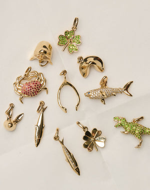 Collectable gold charms with diamonds and green and red gemstones.