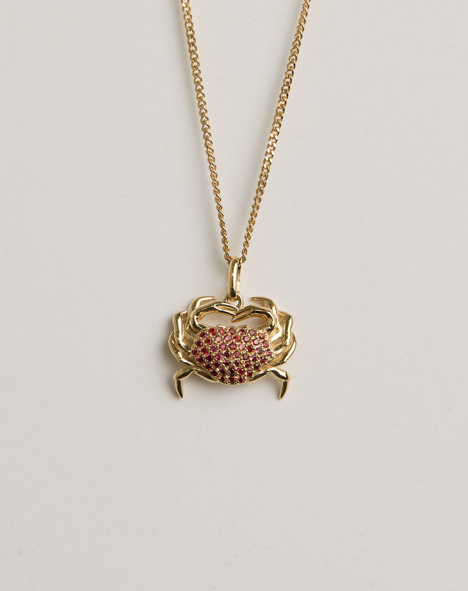 Gold necklace with a crab charm pendant set with red sapphires 