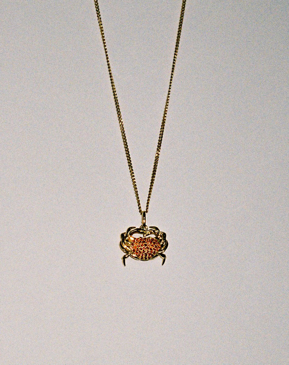 Gold necklace with a crab charm pendant set with red sapphires