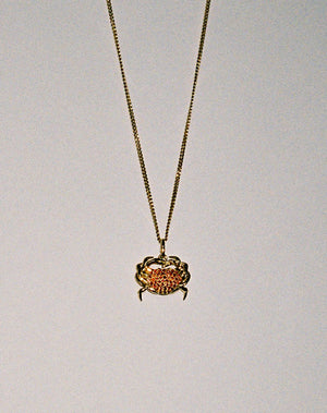 Gold necklace with a crab charm pendant set with red sapphires