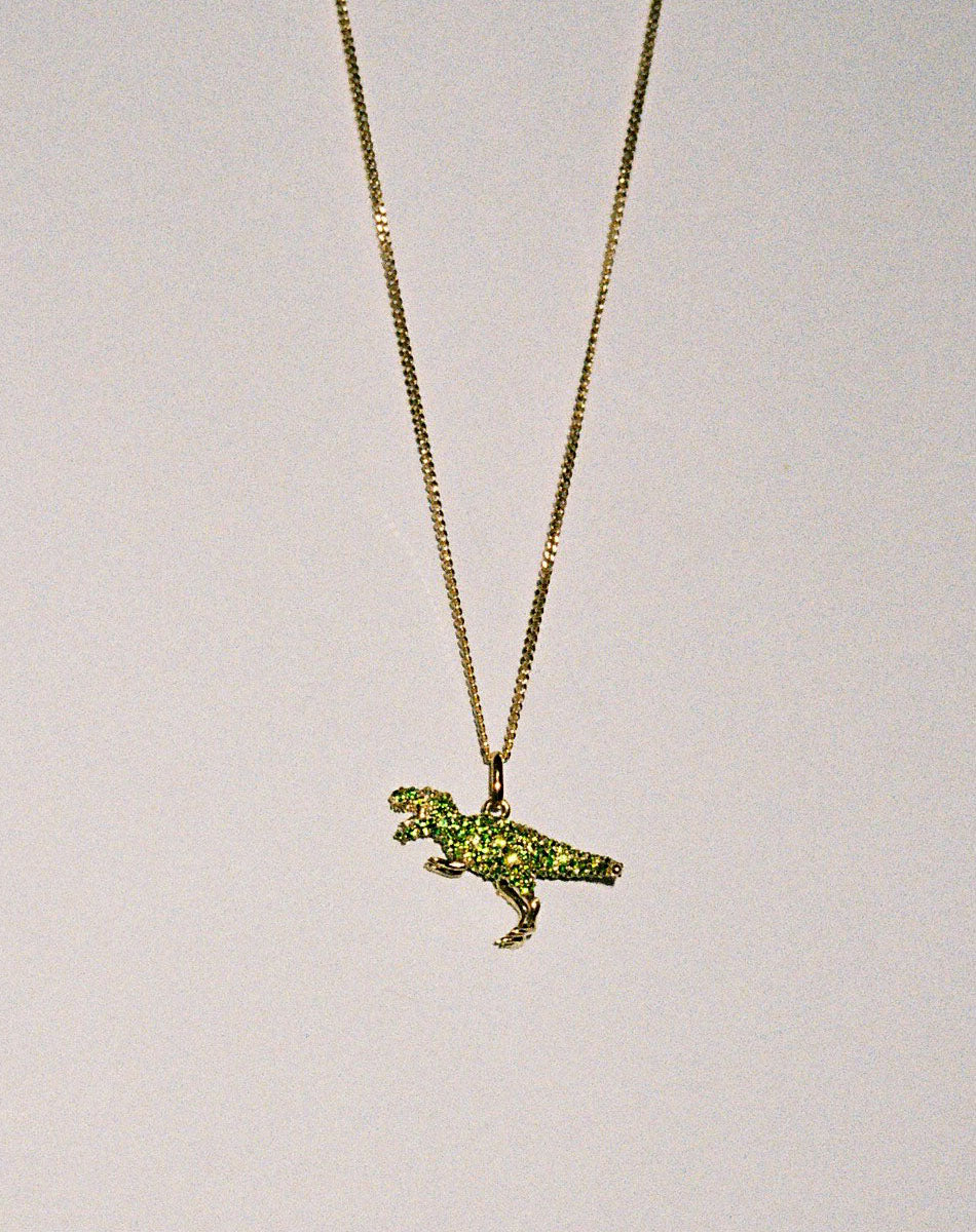Gold dinosaur pendant necklace with green gemstones  