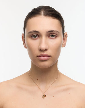 Woman wearing a gold necklace with a lucky fortune cookie pendant on a white background