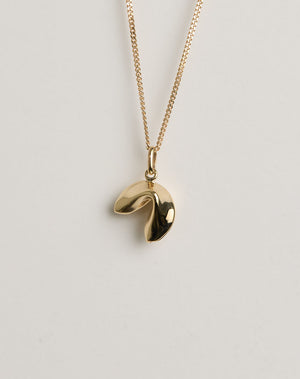 Gold necklace with a lucky fortune cookie pendant on a light grey background
