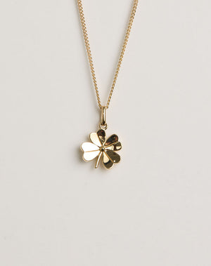 Gold four-leaf clover necklace on a light grey background