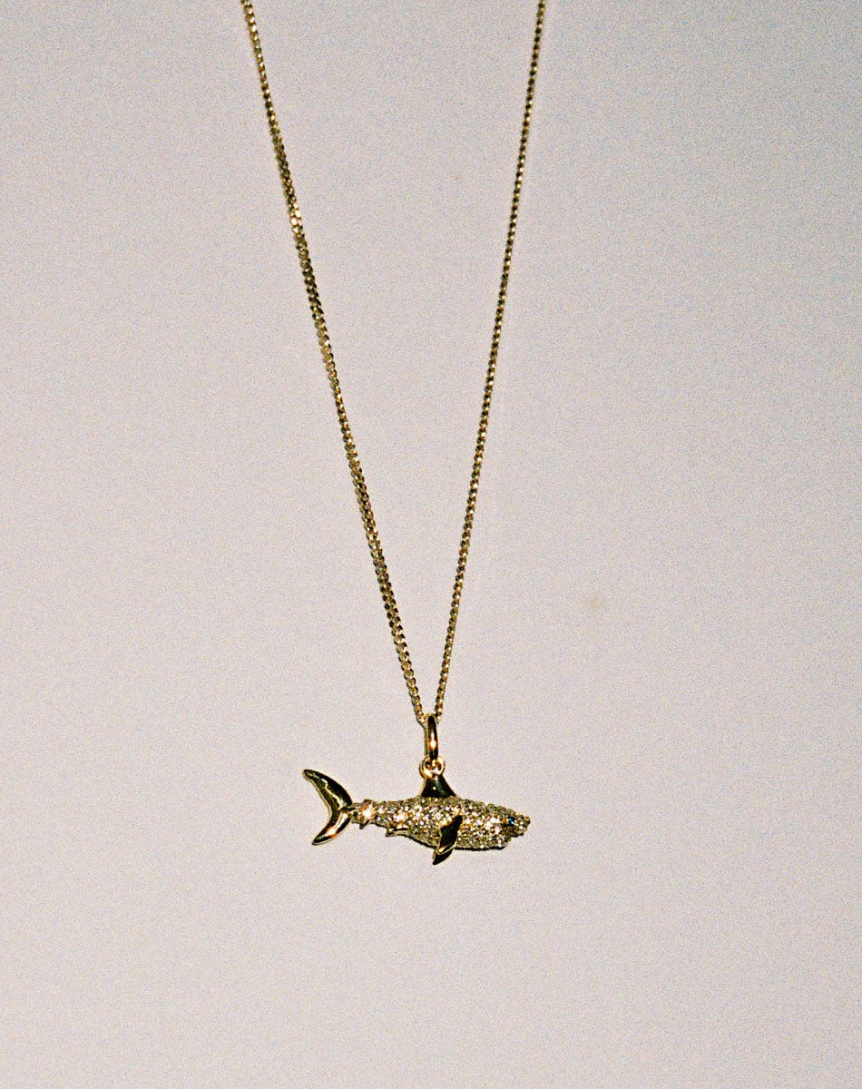 Gold and diamond shark charm pendant necklace.