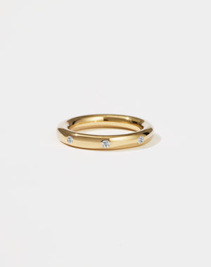 Gold ring with embedded diamonds on a light beige background