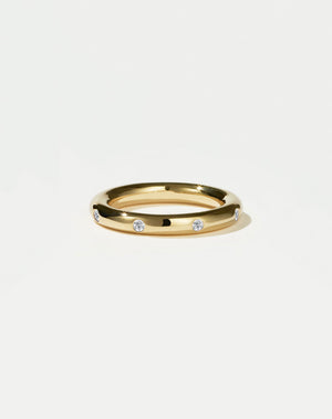Gold ring with embedded diamonds on a light grey background