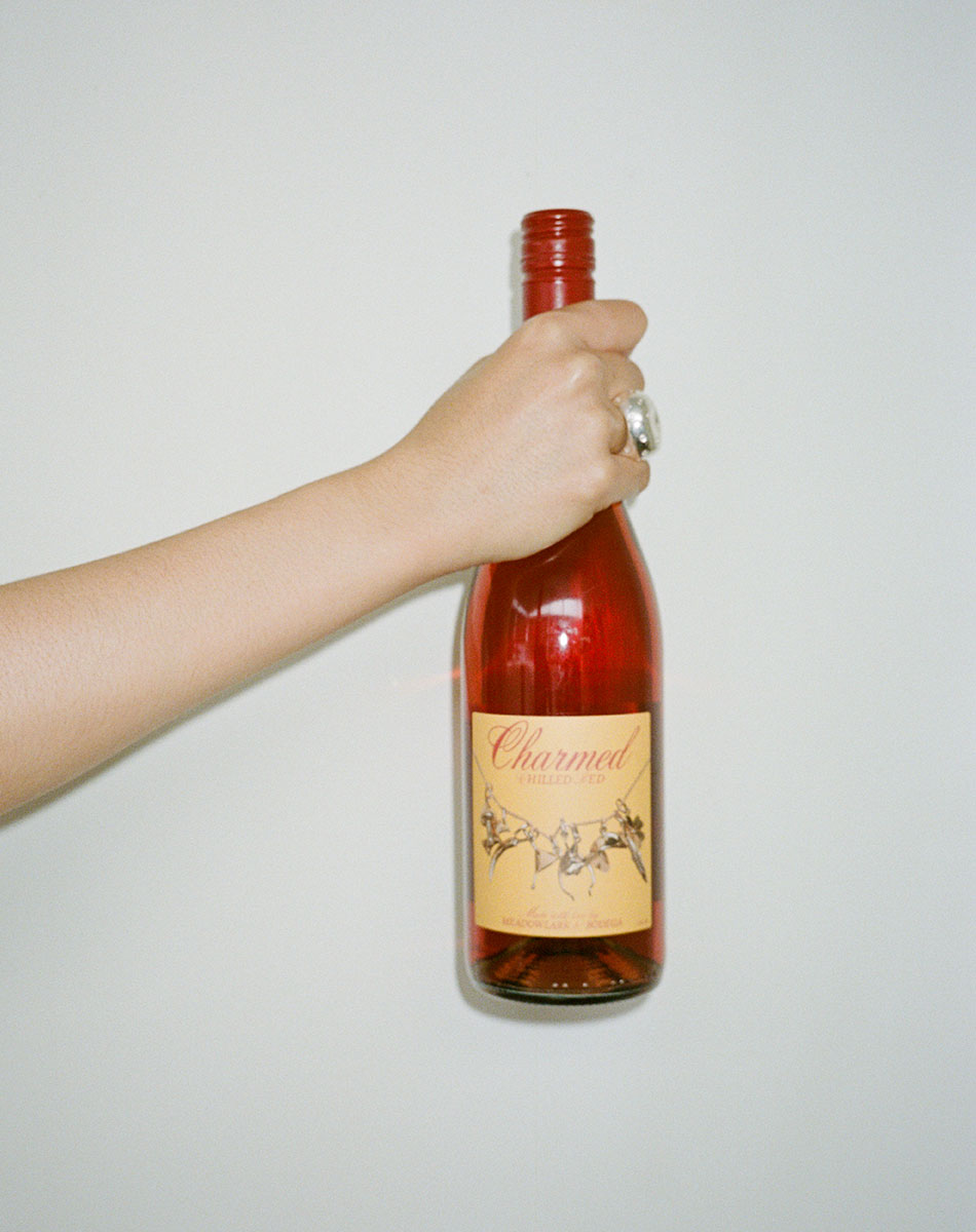 Hand holding a bottle of chilled red wine by Meadowlark against a plain background