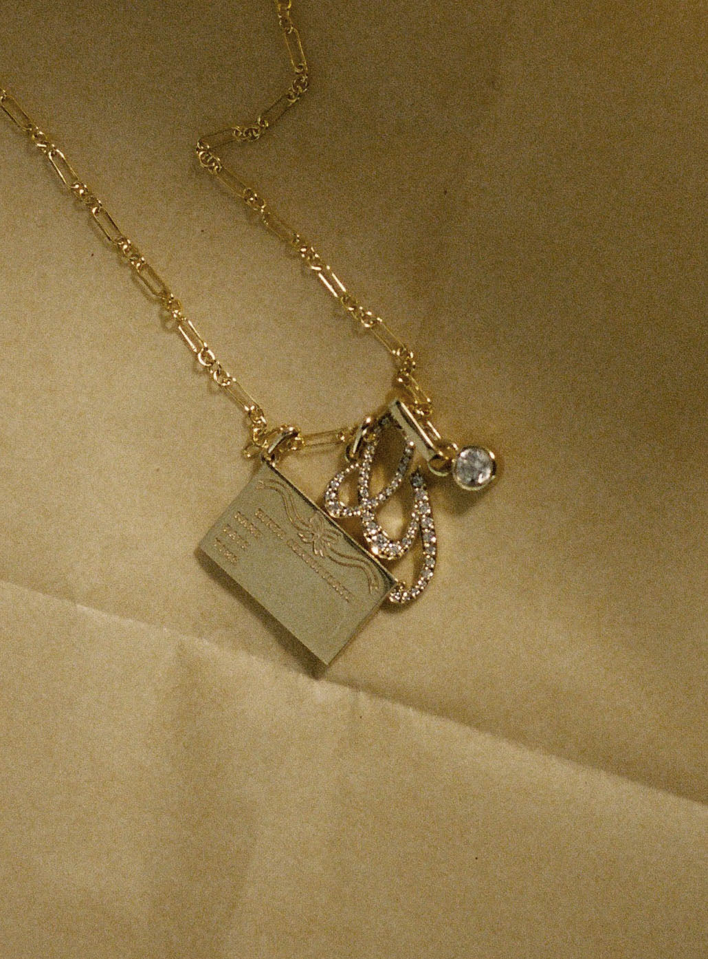 Gold necklace with charms on a beige background