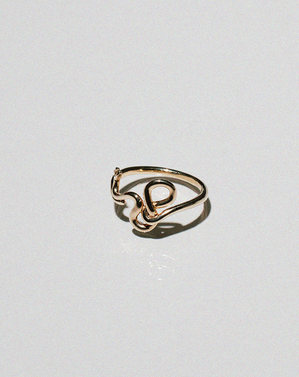 Gold snake ring curving and wrapping into a band.