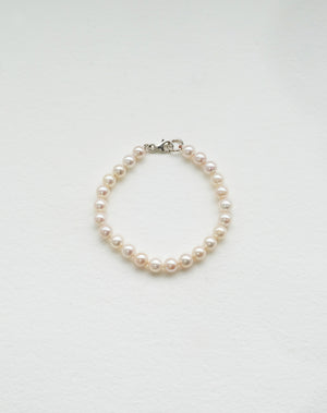 A bracelet featuring round freshwater pearls strung on silk thread with sterling silver clasp.