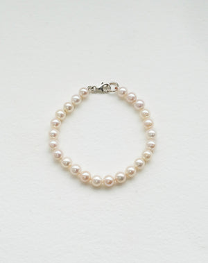 A sterling silver pearl anklet featuring a series of round pearls strung on a silk thread with a classical knotting 
