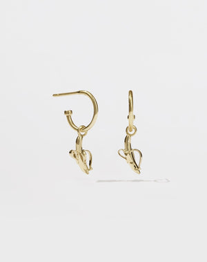 A pair of gold hoop earrings with a small gold-colored banana charm hanging from each hoop.