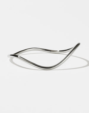 A sterling silver bracelet with a minimalist design that transitions into a curvy, rounded band.