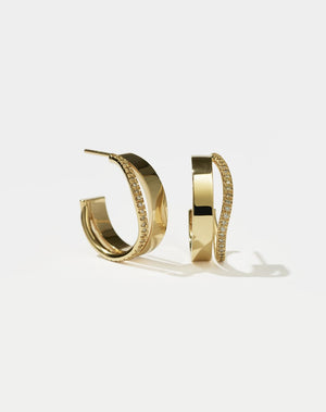 A pair of gold hoop earrings with a pave of diamonds set on the hoops.