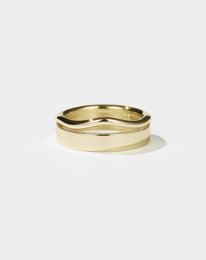 A gold ring with a flat, minimalist band and an organic, curvy rounded band, appearing as one sleek form.