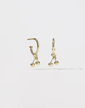 A pair of gold-plated hoop earrings with cherry charms attached