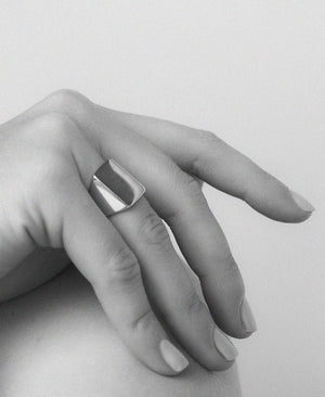 An oversized sterling silver signet ring with a flat rectangular platform for engraving, shown on a hand