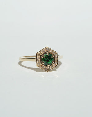 Meadowlark Jewellery’s Limited Edition Hex Engagement Ring 0.5ct in 9ct Yellow Gold, claw set with a round brilliant cut Tsavorite emerald Garnet centre stone, surrounded by a hexagon halo of pave set white diamonds. One of our most iconic and modern Ceremonial designs, made to order in New Zealand. Pair with our bestseller, the Diamond Eternity Band.