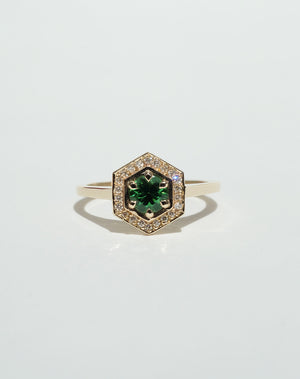 Meadowlark Jewellery’s Limited Edition Hex Engagement Ring 0.5ct in 9ct Yellow Gold, claw set with a round brilliant cut Tsavorite emerald Garnet centre stone, surrounded by a hexagon halo of pave set white diamonds. One of our most iconic and modern Ceremonial designs, made to order in New Zealand. Pair with our bestseller, the Diamond Eternity Band.