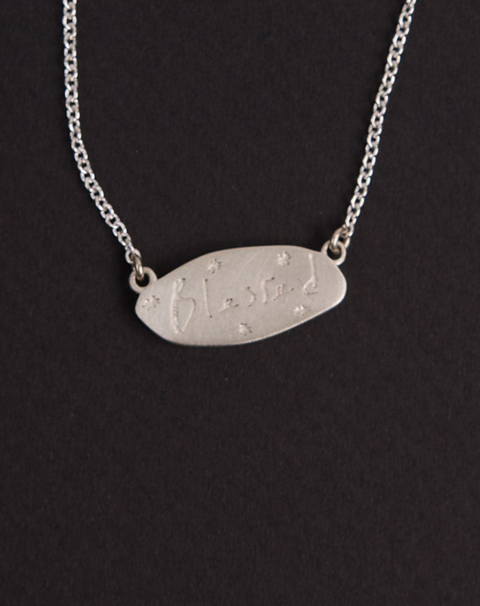 Meadowlark Jewellery’s Blessed Necklace in Sterling Silver. A meaningful talisman for life’s journey, to serve as a daily reminder to honour the present and embrace gratitude for the quiet abundance all around us. A classic name tag in a matte, brushed texture inspired by ancient heirlooms hung from a fine diamond curb chain. From the Dreams collection.