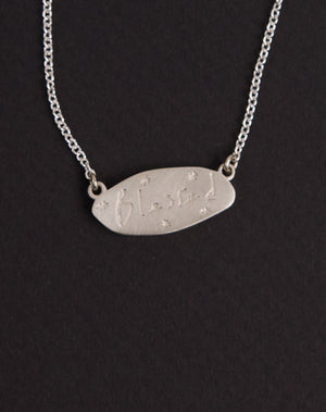 Meadowlark Jewellery’s Blessed Necklace in Sterling Silver. A meaningful talisman for life’s journey, to serve as a daily reminder to honour the present and embrace gratitude for the quiet abundance all around us. A classic name tag in a matte, brushed texture inspired by ancient heirlooms hung from a fine diamond curb chain. From the Dreams collection.