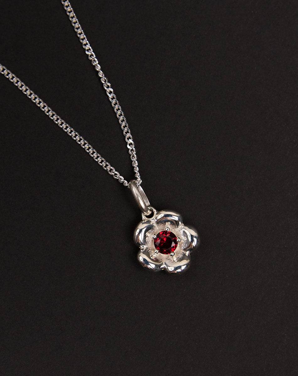 Meadowlark Jewellery’s floral Posie Charm Necklace in Sterling Silver, set with a single round brilliant cut African Garnet stone. Hung from a fine diamond curb chain. Inspired by classic floral motifs and our beloved Alba designs, a timeless symbol of grace, growth and renewal. Celebrating life’s continual renewal. From the Dreams collection.