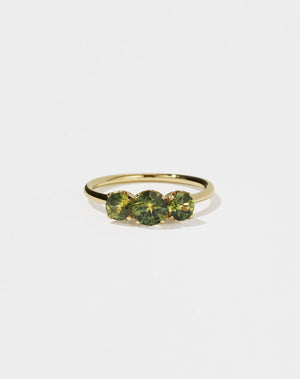 A classic three stone engagement ring in yellow gold with green sapphire.