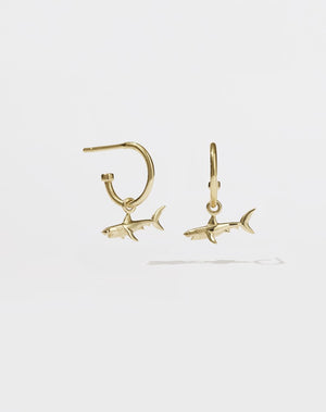 A pair of gold hoop earrings with shark charms attached