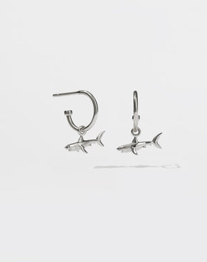 A pair of sterling silver hoop earrings with shark charms attached to them