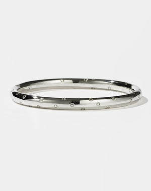 A sterling silver bangle bracelet with a pattern of circles around it, resembling strawberry seeds.