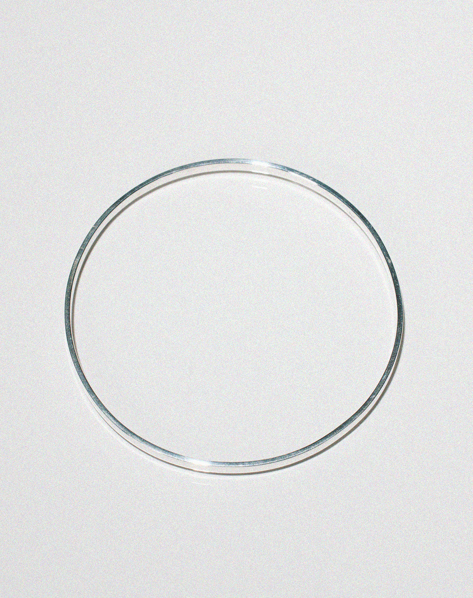 Silver flat bangle shown side on.
