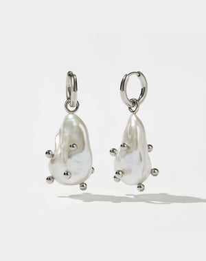 A pair of sterling silver drop earrings featuring baroque pearls with barnacles.