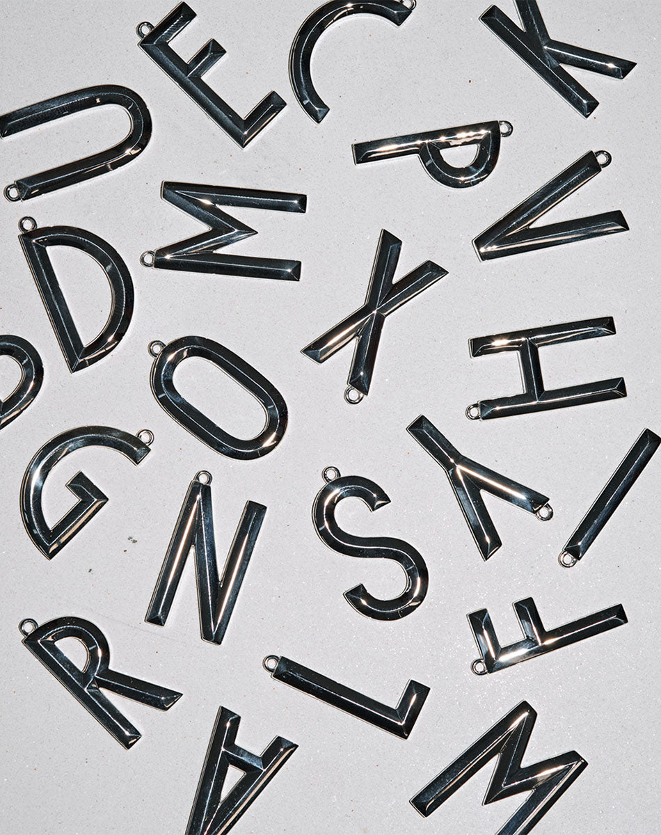 Silver pendants in the shape of letters, with a faceted design.