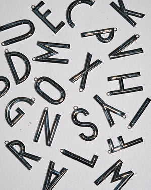 Silver pendants in the shape of letters, with a faceted design.