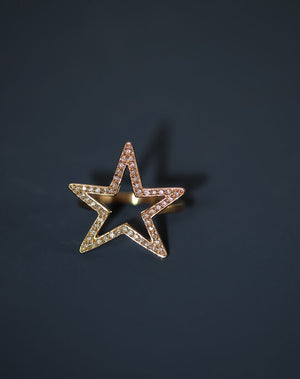 Close up of a gold star ring set with white diamonds.