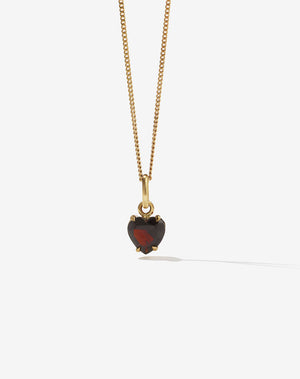 A heart-shaped Thai Garnet necklace in a claw setting, suspended from a gold chain 
