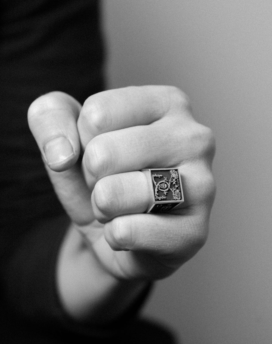 A heavy weighted sterling silver ring with a black and white collage artwork design. Worn on hand.